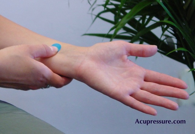 Woman holding acupressure point near wrist.